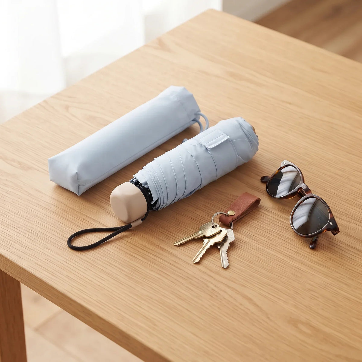 Umbrellys pocket umbrella folded on a table with its sleeve, keys and sunglasses